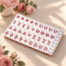 White Mahjong tiles arranged in rows of red-and-blue circle patterns and outlined rectangular faces beside pink roses.
