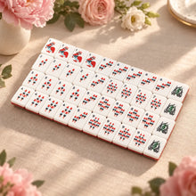 American Mahjong bamboo tiles in red and teal rows, with floral end tiles and pink roses around the display.