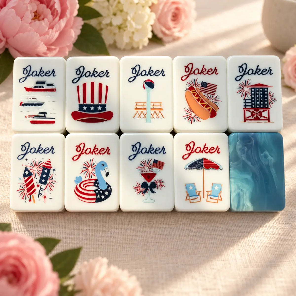 Nine patriotic Mahjong Joker tiles with fireworks, flags, a hot dog and beach imagery beside a blue marbled tile back.