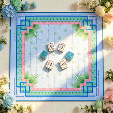 Square blue Mahjong mat with a pink border, palm fronds and geometric corners, shown with wind tiles and blue-backed tiles.